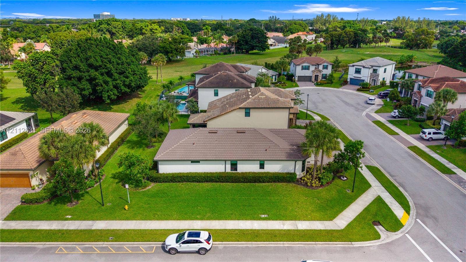 8257 NW 79th Avenue, Tamarac, FL 33321 Corner lot residence featuring a tile roof, multi-car garage, manicured landscaping, and expansive green space