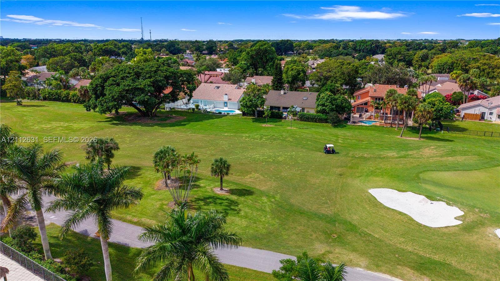 8257 NW 79th Avenue, Tamarac, FL 33321 Aerial perspective of a golf course setting featuring expansive green fairways, sand bunkers, mature trees, and landscaped palms