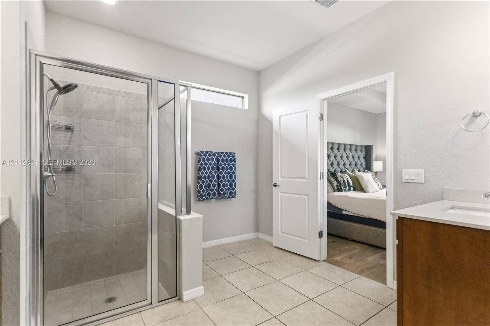 8257 NW 79th Avenue, Tamarac, FL 33321 Walk-in shower with floor-to-ceiling ceramic tile surround and chrome fixtures, wood-finish vanity with countertop sink, and neutral ceramic tile flooring