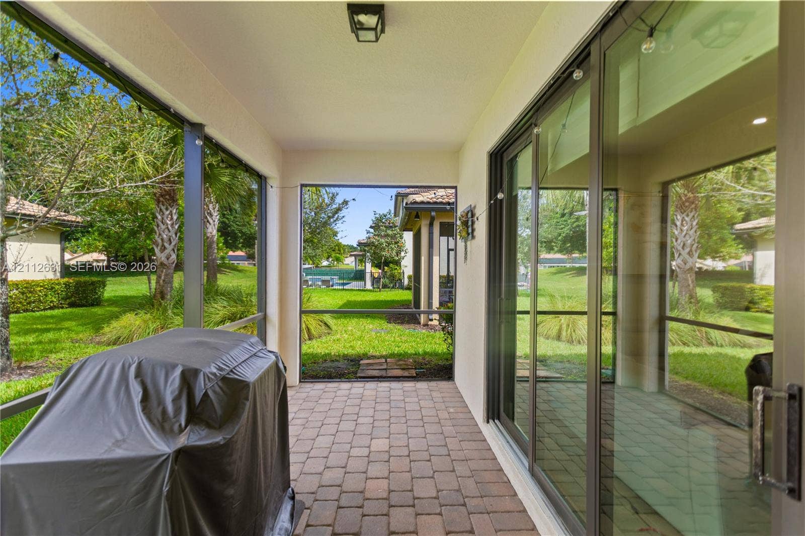 8257 NW 79th Avenue, Tamarac, FL 33321 Screened-in lanai featuring paver flooring, overhead lighting, and multi-panel sliding glass doors