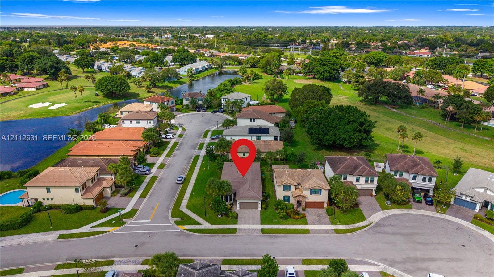 8257 NW 79th Avenue, Tamarac, FL 33321 Aerial perspective of a single-family residence featuring a paved driveway, attached multi-car garage, and a hip roof, situated on a residential cul-de-sac