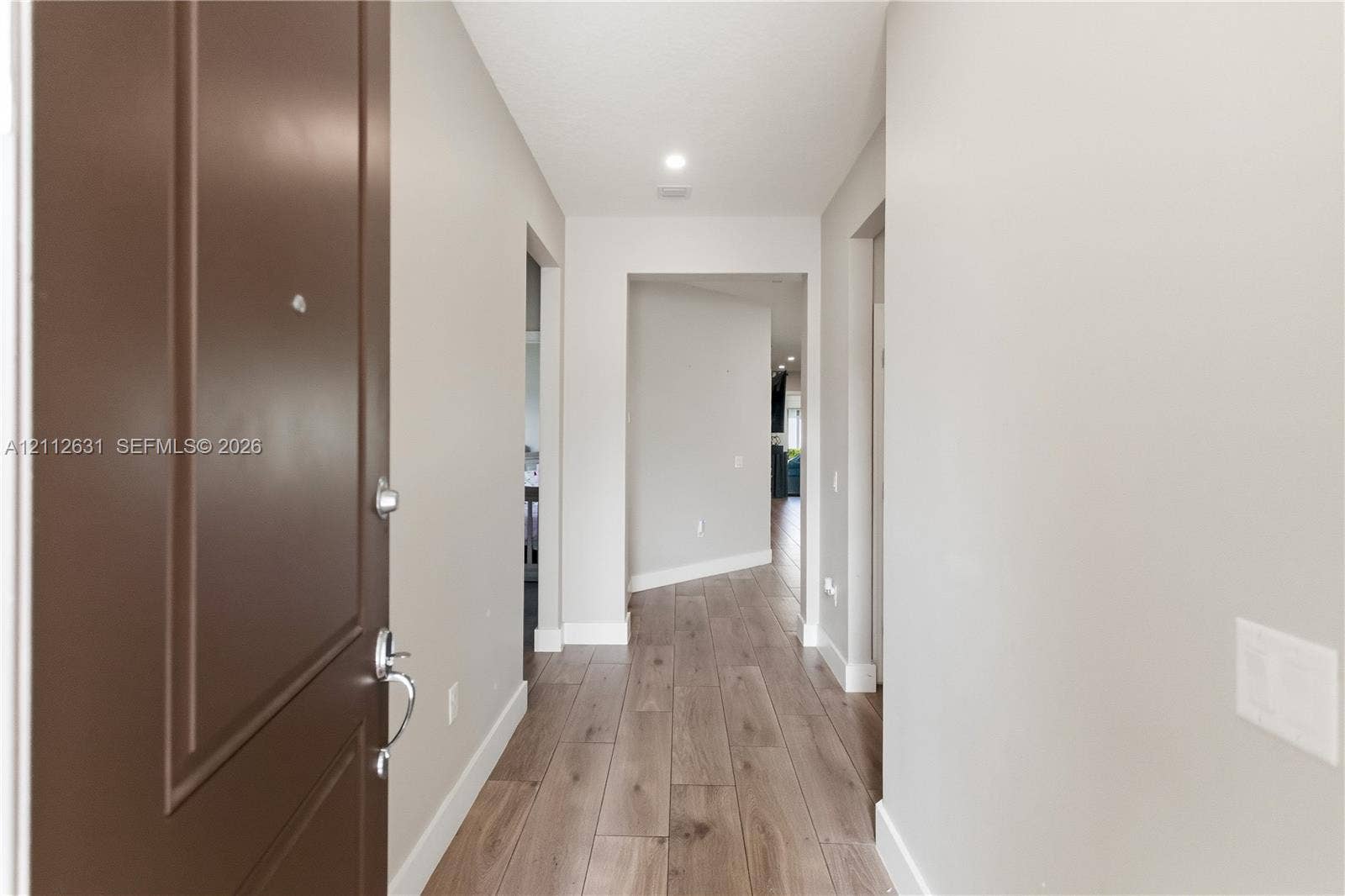 8257 NW 79th Avenue, Tamarac, FL 33321 Entry foyer featuring wood-finish flooring, a solid-panel door with metallic hardware, neutral wall paint, and recessed ceiling lighting