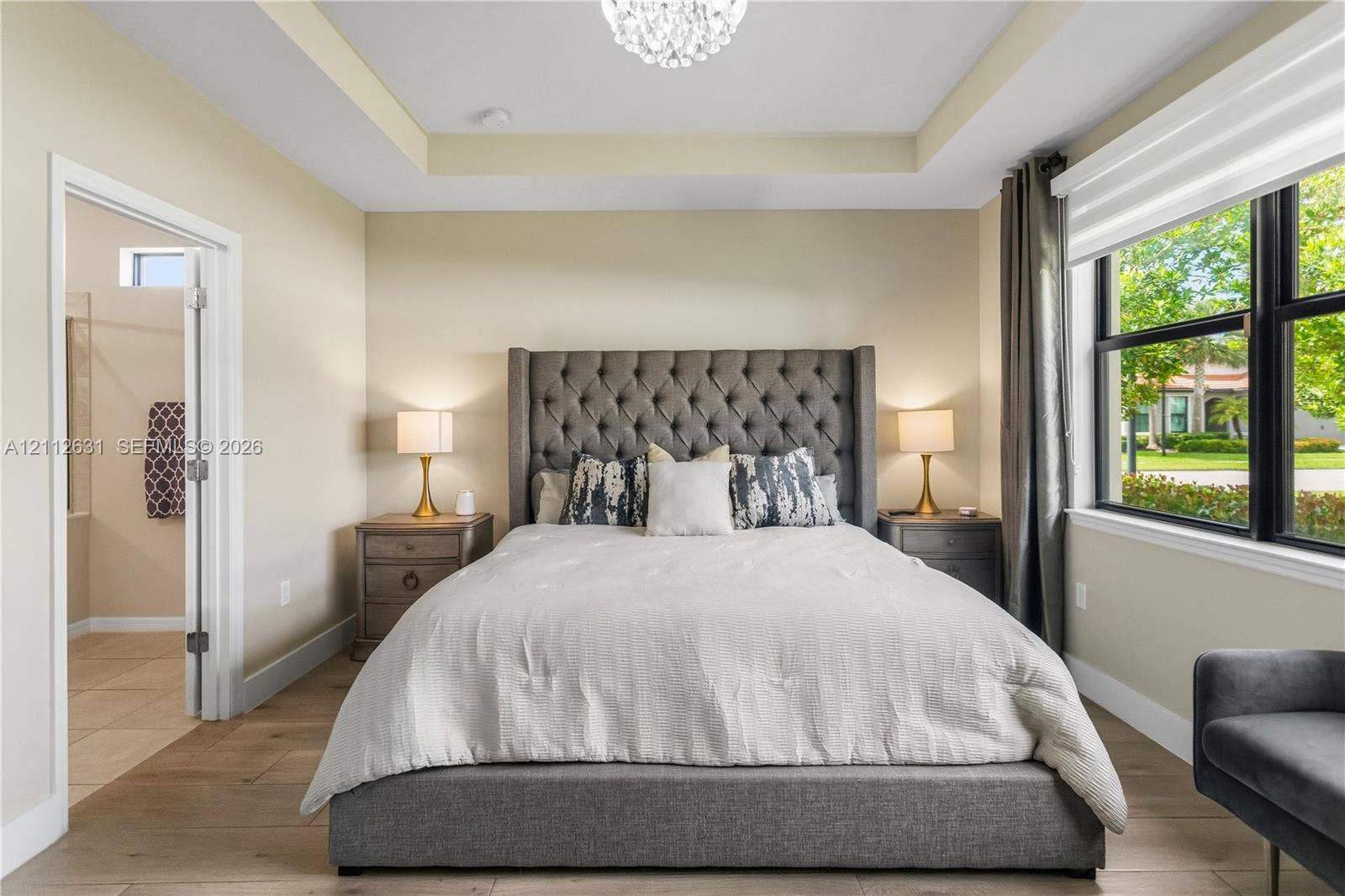 8257 NW 79th Avenue, Tamarac, FL 33321 Tray ceiling featuring a central chandelier, wood-finish flooring, and black-trimmed windows