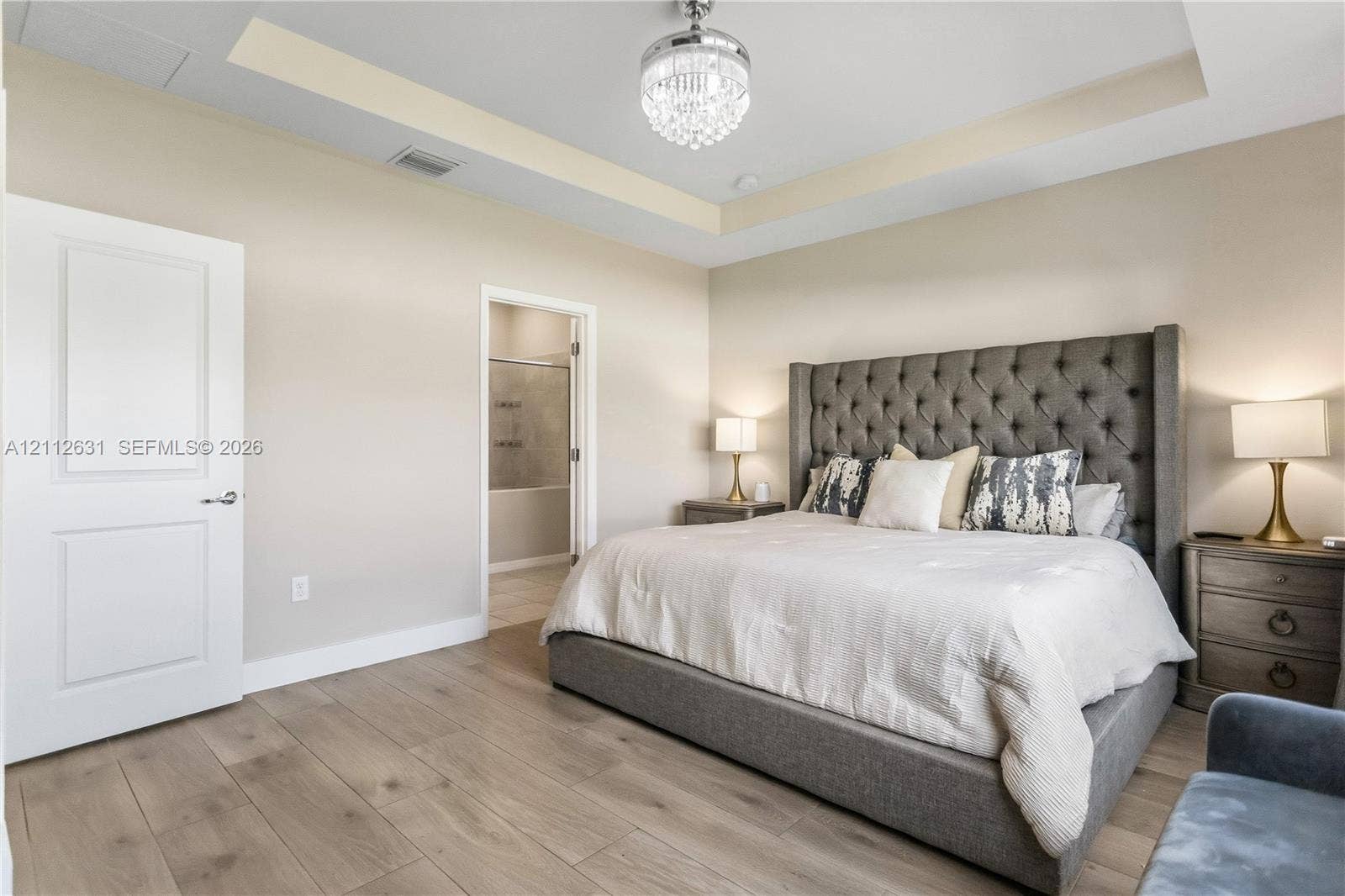 8257 NW 79th Avenue, Tamarac, FL 33321 Tray ceiling featuring a recessed design, wood-finish flooring, and a decorative crystal chandelier