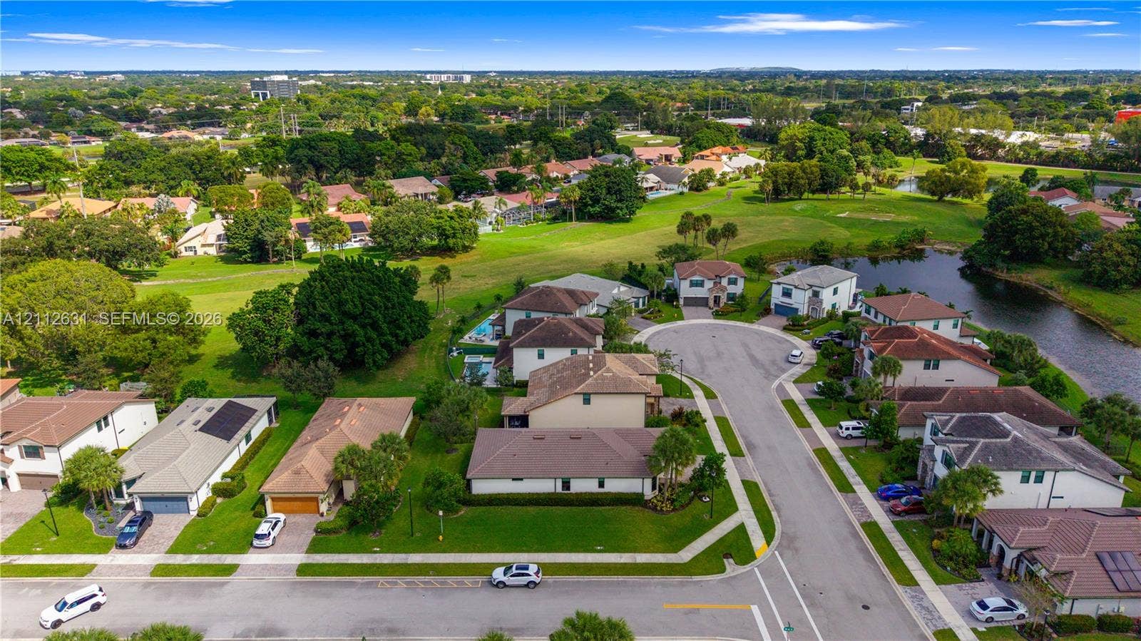 8257 NW 79th Avenue, Tamarac, FL 33321 Aerial perspective of a residential community featuring expansive green spaces, manicured landscaping, a winding water feature, and paved cul-de-sac streets