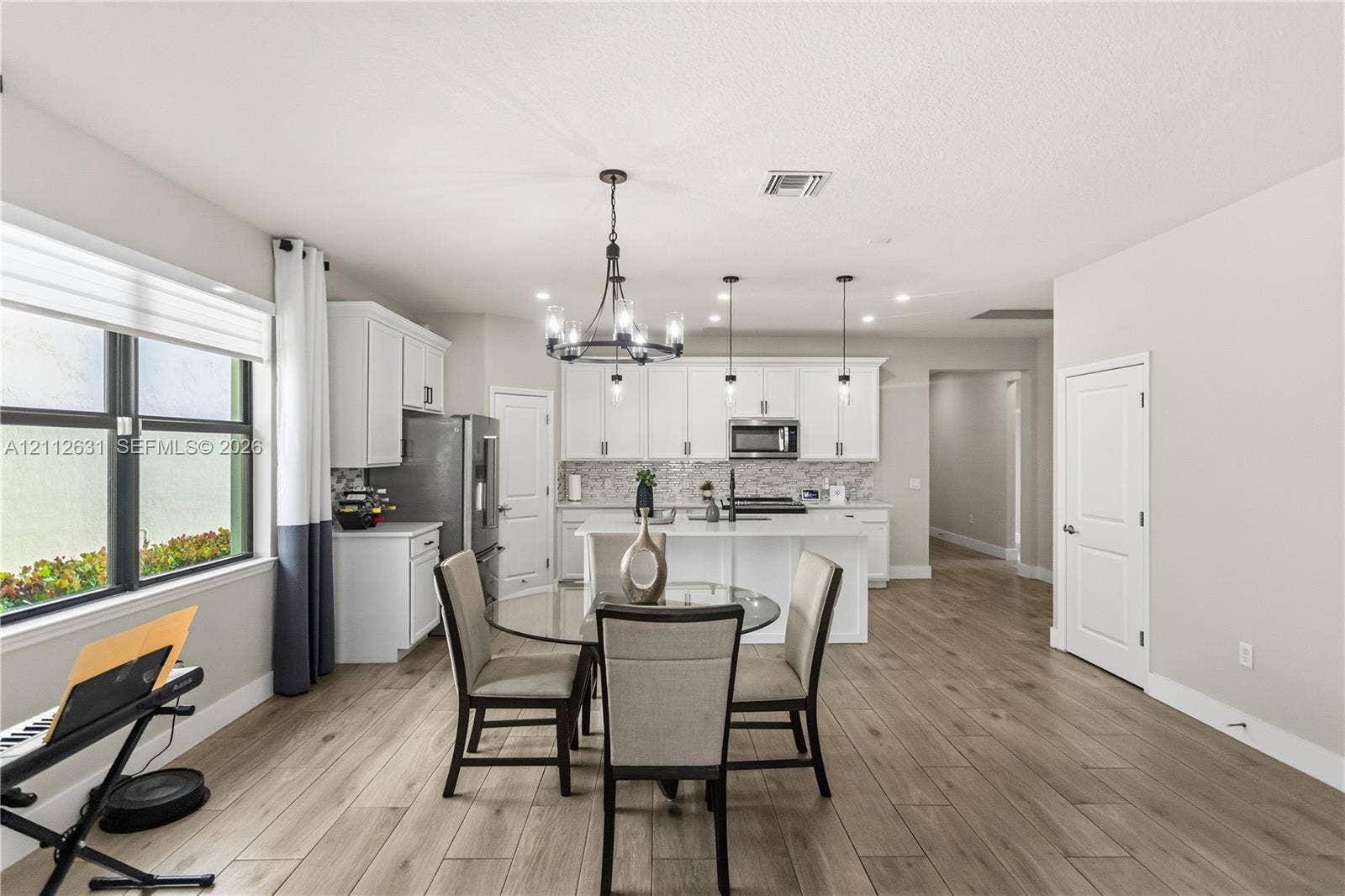 8257 NW 79th Avenue, Tamarac, FL 33321 Kitchen featuring white cabinetry, center island with quartz countertops, wood-finish flooring, and decorative chandelier lighting