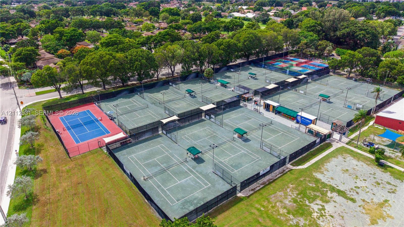 8257 NW 79th Avenue, Tamarac, FL 33321 Multi-court tennis facility featuring high-fencing enclosures, integrated court lighting, paved walkways, and shade structures