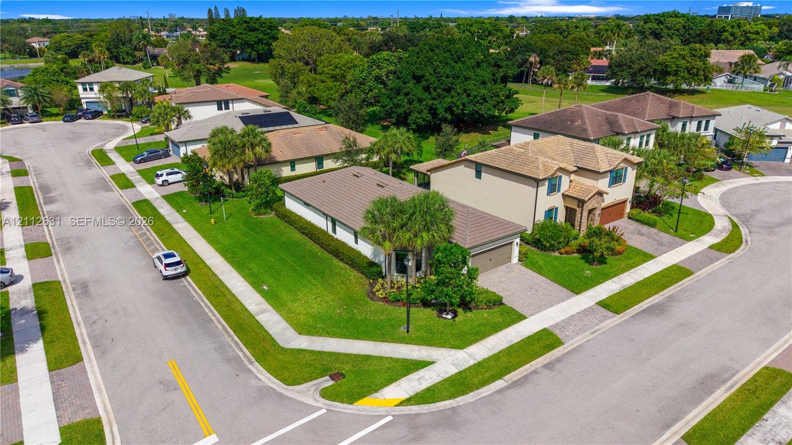 8257 NW 79th Avenue, Tamarac, FL 33321 Corner lot residence featuring a paved driveway, tile roofing, manicured lawn, and perimeter landscaping