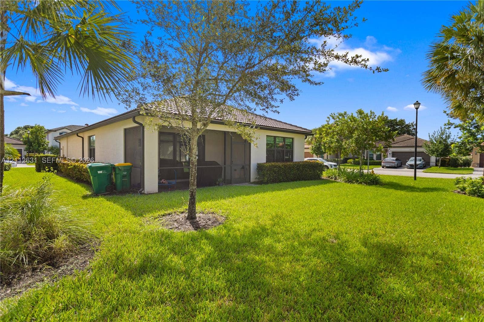 8257 NW 79th Avenue, Tamarac, FL 33321 Stucco exterior featuring a tiled roof, screened-in porch, mature landscaping, and an expansive lawn