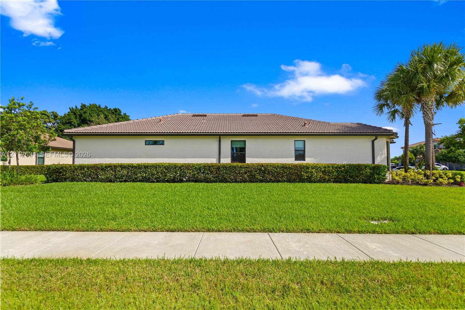 8257 NW 79th Avenue, Tamarac, FL 33321 Exterior elevation featuring a tile roof, stucco siding, and a manicured hedge border