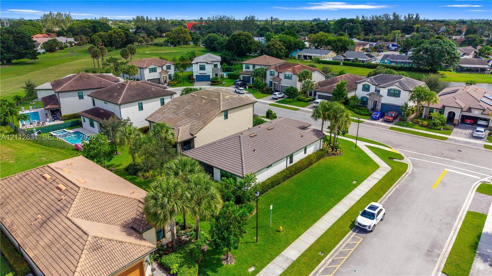 8257 NW 79th Avenue, Tamarac, FL 33321 Aerial perspective of a residential neighborhood featuring multi-story dwellings, tile roofing, manicured green spaces, and palm tree landscaping