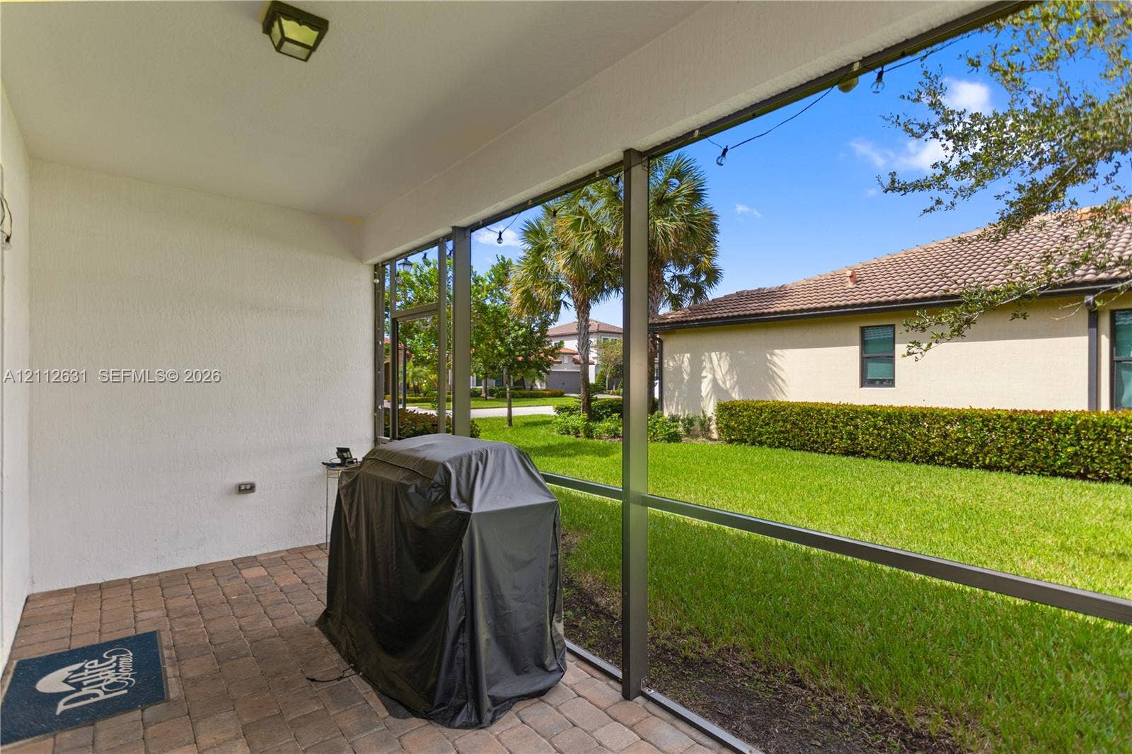 8257 NW 79th Avenue, Tamarac, FL 33321 Screen-enclosed covered patio featuring paver flooring, stucco walls, and an exterior light fixture