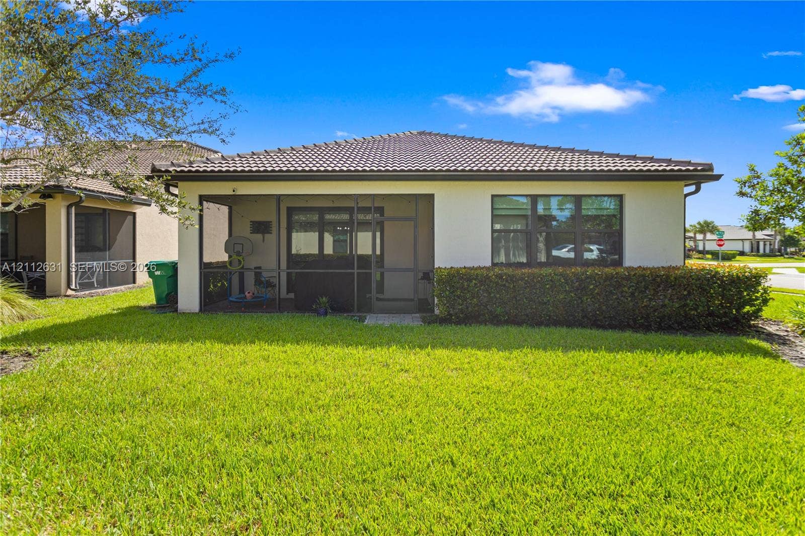 8257 NW 79th Avenue, Tamarac, FL 33321 Exterior rear elevation featuring a screened-in lanai, stucco facade, tiled roof, and manicured lawn
