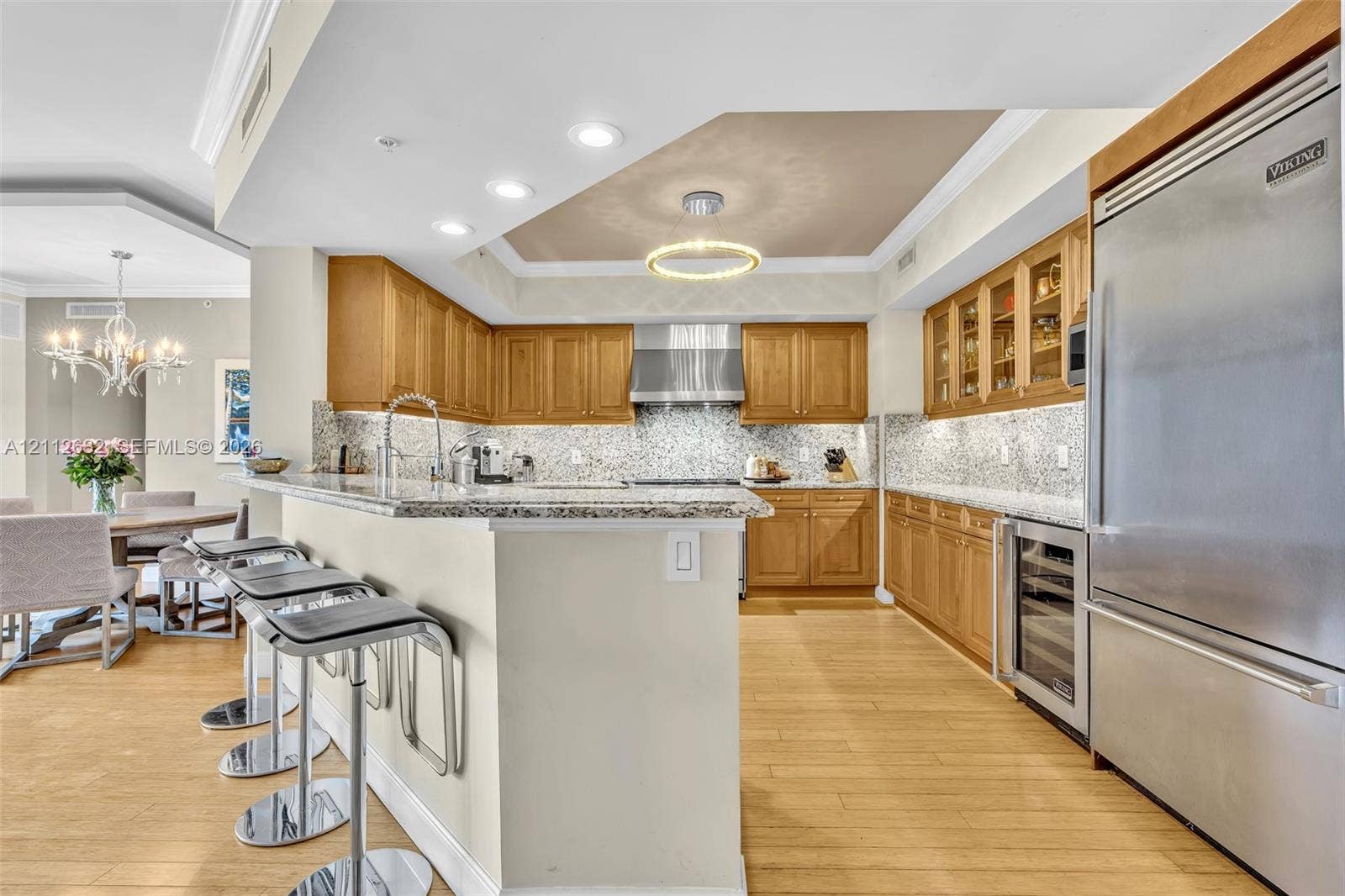 Kitchen featuring wood cabinetry, stone countertops, stainless steel professional-grade refrigerator, built-in wine cooler, and wood-finish flooring