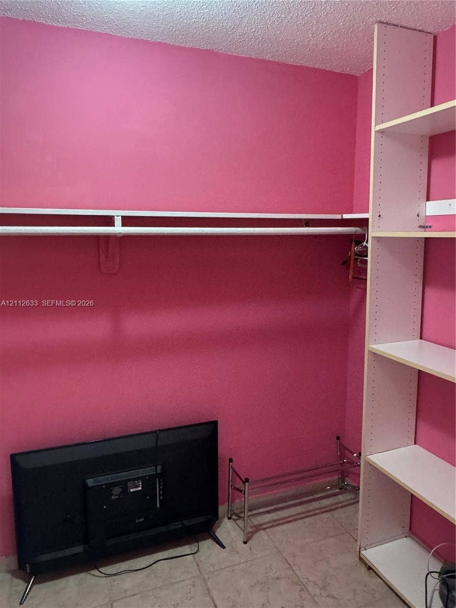 1770 NE 191st Street, #104-1, Miami, FL 33179 Storage area featuring built-in vertical shelving, a horizontal clothes rod, and tile flooring
