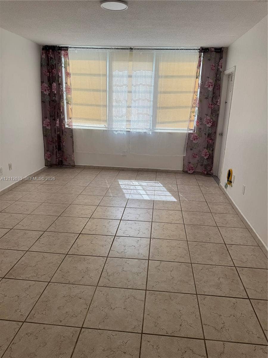 1770 NE 191st Street, #104-1, Miami, FL 33179 Neutral interior space featuring large-format ceramic tile flooring and floor-to-ceiling windows