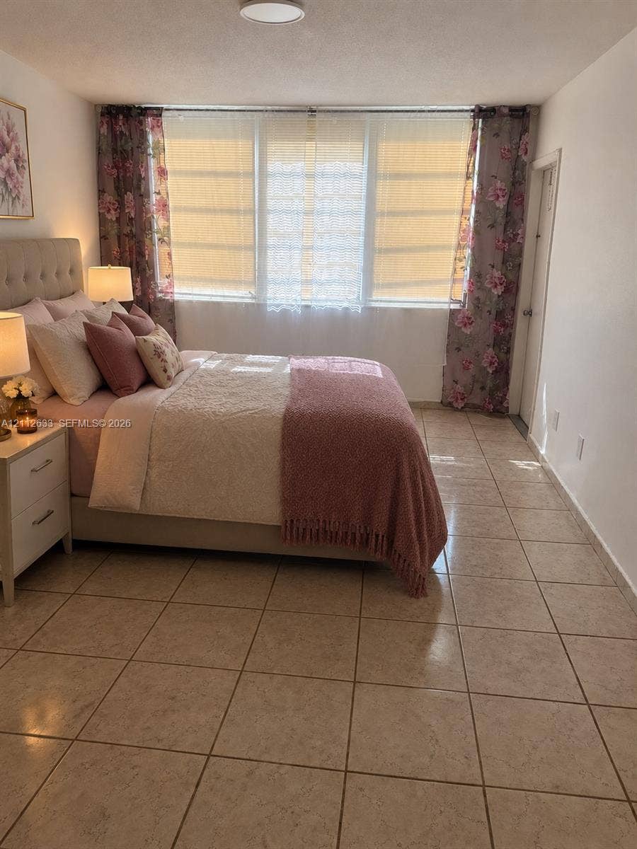 1770 NE 191st Street, #104-1, Miami, FL 33179 Spacious room featuring oversized windows with natural light, neutral ceramic tile flooring, and flush-mount ceiling lighting