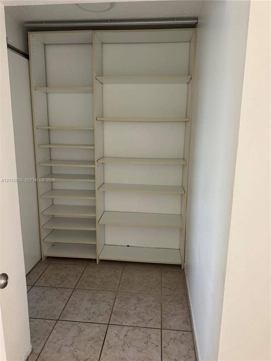 1770 NE 191st Street, #104-1, Miami, FL 33179 Built-in white storage shelving featuring adjustable shelving units and tiled flooring