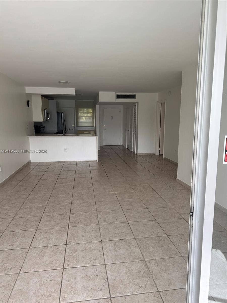 1770 NE 191st Street, #104-1, Miami, FL 33179 Open-concept interior featuring large-format ceramic tile flooring, neutral wall finishes, and a breakfast bar peninsula