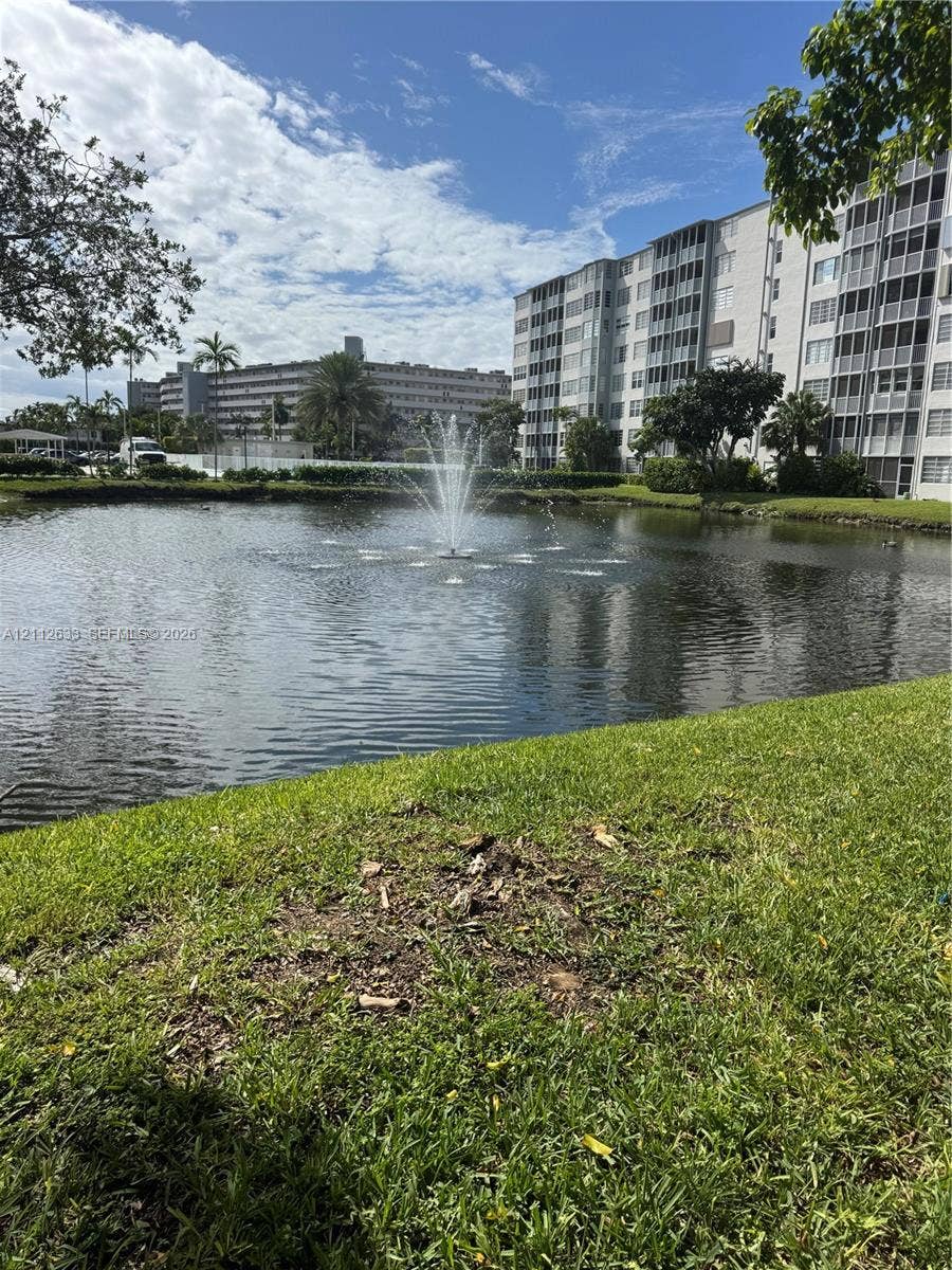 1770 NE 191st Street, #104-1, Miami, FL 33179 Water feature with a central fountain situated within a community pond, surrounded by landscaped lawn and mature trees