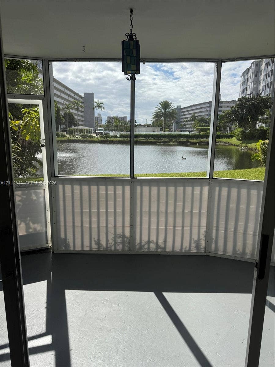 1770 NE 191st Street, #104-1, Miami, FL 33179 Screened-in enclosure featuring a hanging lantern-style light fixture, concrete flooring, and water frontage
