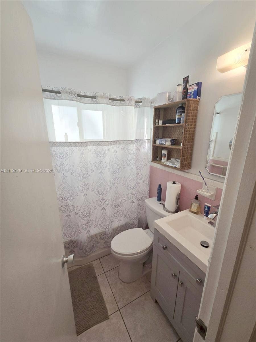 Bathroom featuring a gray vanity with an integrated rectangular sink, tile flooring, and a tub-shower combination with a surround