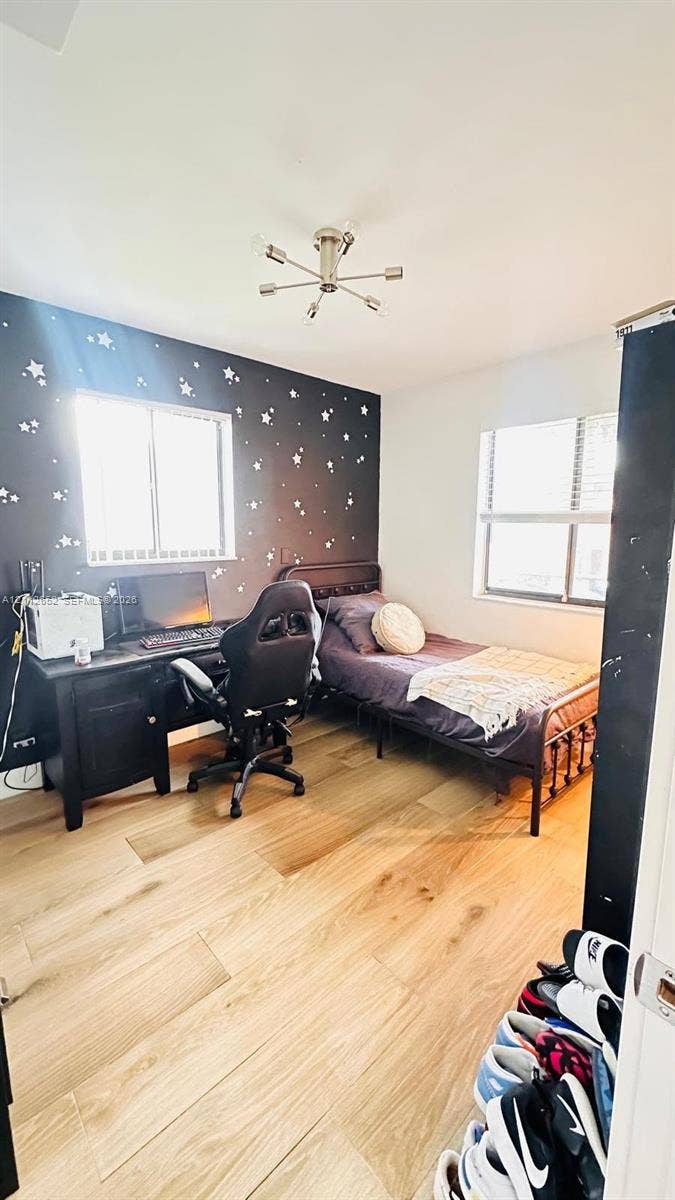 Bedroom featuring wood-finish flooring, dual windows, and a six-arm sputnik-style ceiling light fixture