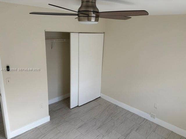 Room featuring wood-finish tile flooring, brushed-nickel ceiling fan with integrated lighting, and a closet with sliding panel doors