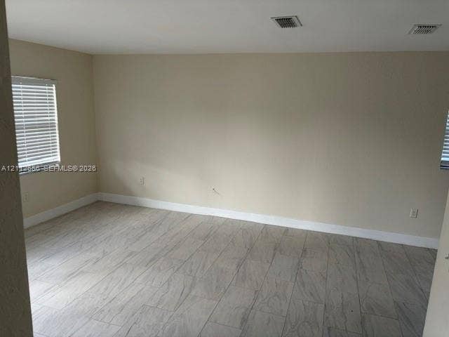 Neutral interior space featuring wood-finish flooring, light-toned walls, and windows with horizontal blinds
