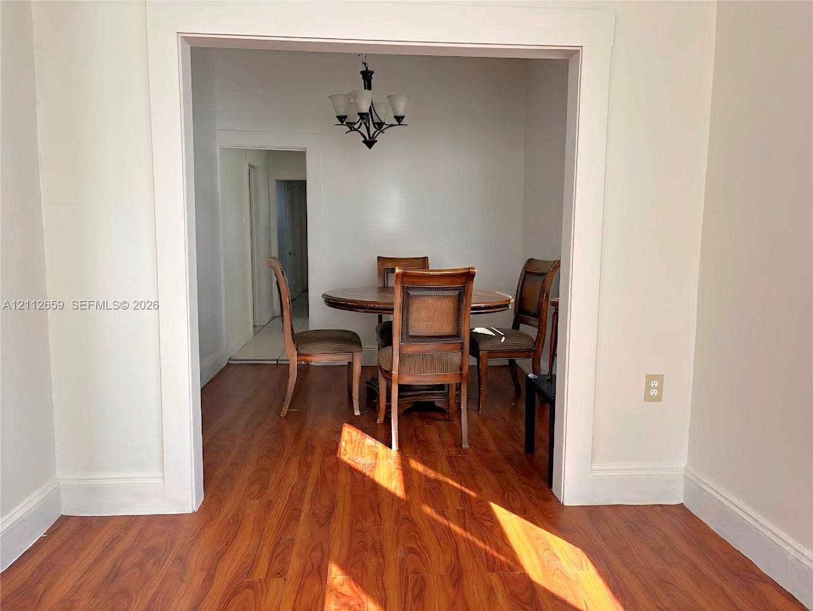 Wood-finish flooring, wide cased openings, and an overhead multi-arm chandelier