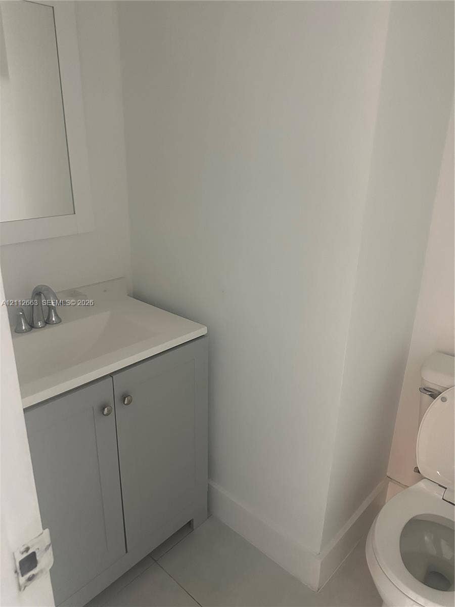 10185 Collins Avenue, #523, Bal Harbour, Bal Harbour, FL 33154 Grey shaker-style vanity with a solid-surface integrated countertop, brushed metal faucet, and wall-mounted mirror