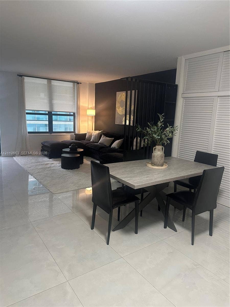 10185 Collins Avenue, #523, Bal Harbour, Bal Harbour, FL 33154 Open-concept interior featuring large-format tile flooring, a black-painted accent wall, built-in louvered-style closet doors, and expansive windows