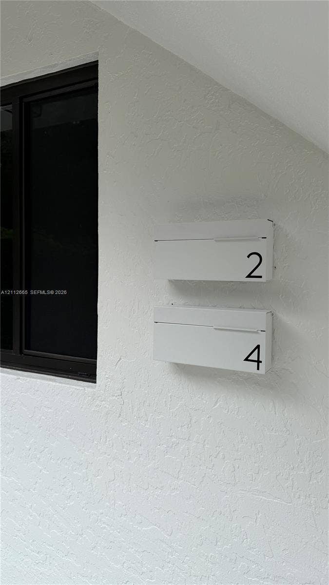 3314 NW 8th, #2, Miami, Miami, FL 33131 Textured white exterior wall featuring dual minimalist white mailboxes with numerical identification and a black-framed window
