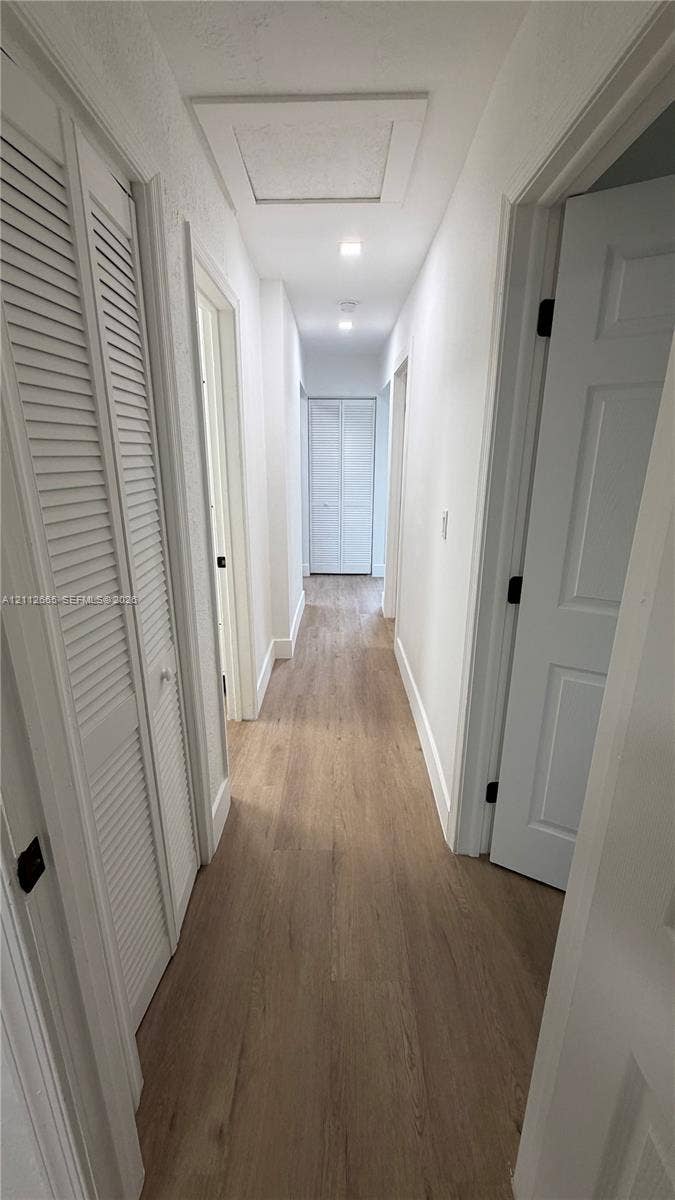 3314 NW 8th, #2, Miami, Miami, FL 33131 Hallway featuring wood-finish flooring, white paneled doors, louvered closet doors, and recessed lighting