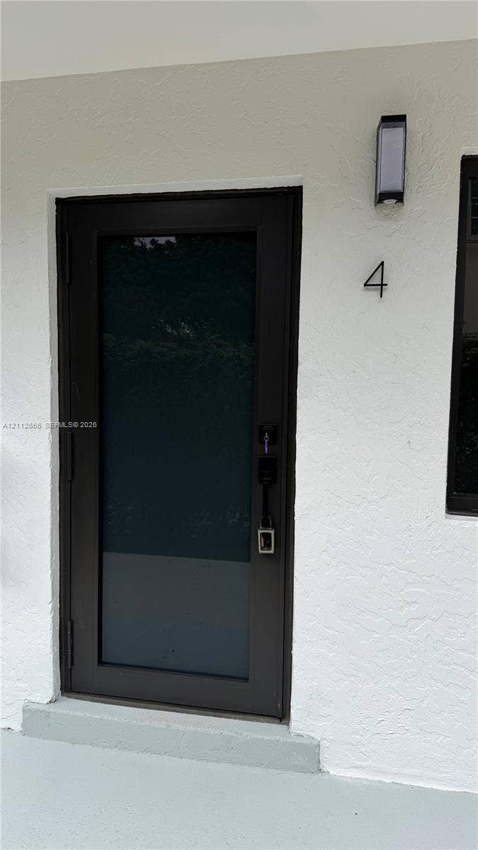 3314 NW 8th, #2, Miami, Miami, FL 33131 Entryway featuring a dark-toned door with glass paneling, stucco exterior wall, and wall-mounted exterior light fixture