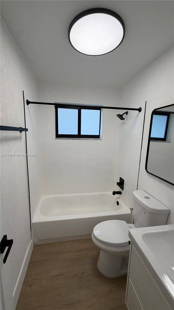 3314 NW 8th, #2, Miami, Miami, FL 33131 Bathroom featuring wood-finish flooring, a white vanity with an integrated countertop sink, matte black hardware, a shower-tub combination with white wall surround, and a circular flush-mount ceiling light