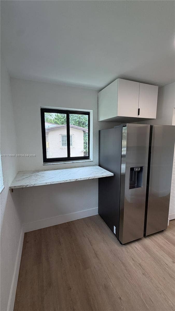 3314 NW 8th, #2, Miami, Miami, FL 33131 Kitchen nook featuring wood-finish flooring, stone-surfaced counter, stainless steel refrigerator, and overhead cabinetry