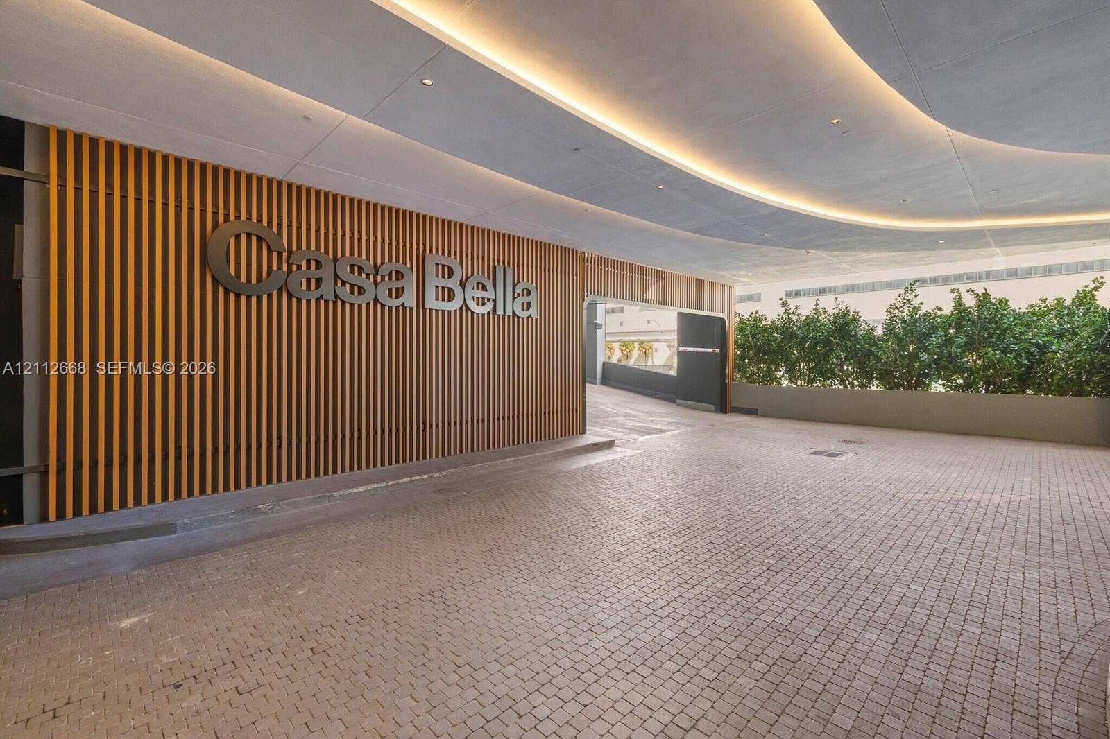 1400 Biscayne Boulevard, #1803, Miami, Miami, FL 33132 Covered arrival entrance featuring a stone paver driveway, vertical wood-slat wall accents, recessed architectural lighting, and integrated landscaping