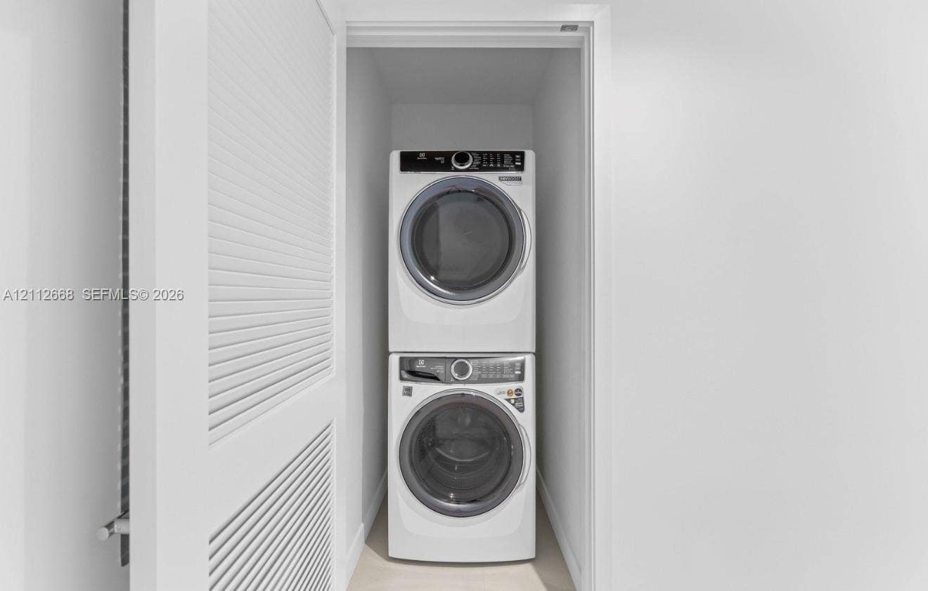 1400 Biscayne Boulevard, #1803, Miami, Miami, FL 33132 Laundry closet featuring a stacked washer and dryer set, neutral wall finish, and white louvered door