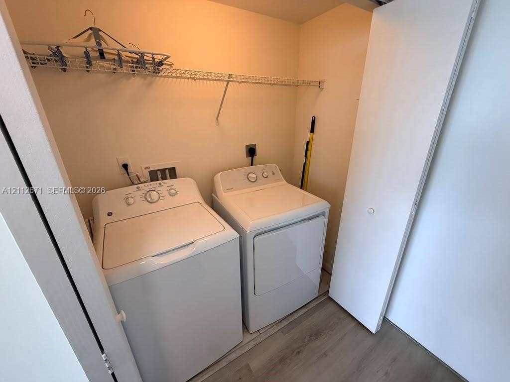 Laundry closet featuring wood-finish flooring, white bi-fold door, and built-in wire shelving