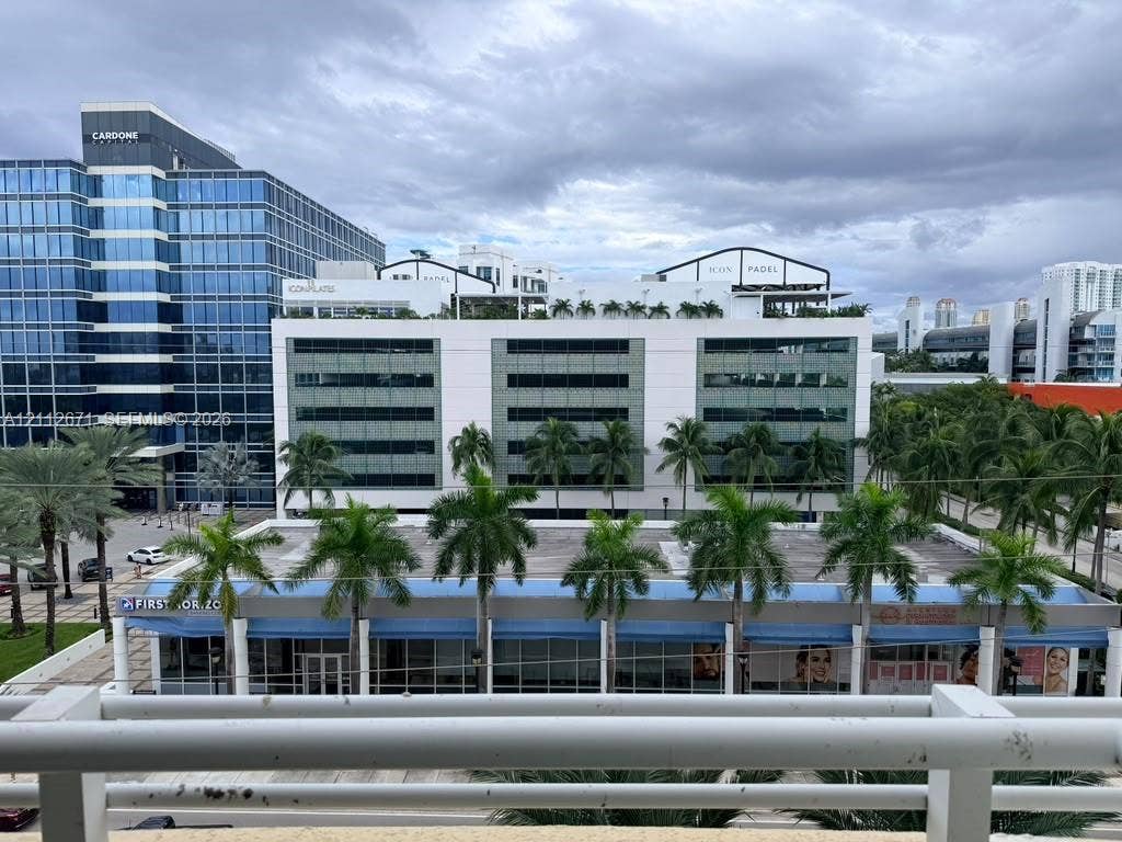 Elevated balcony featuring a white metal railing and a direct perspective of the surrounding urban landscape