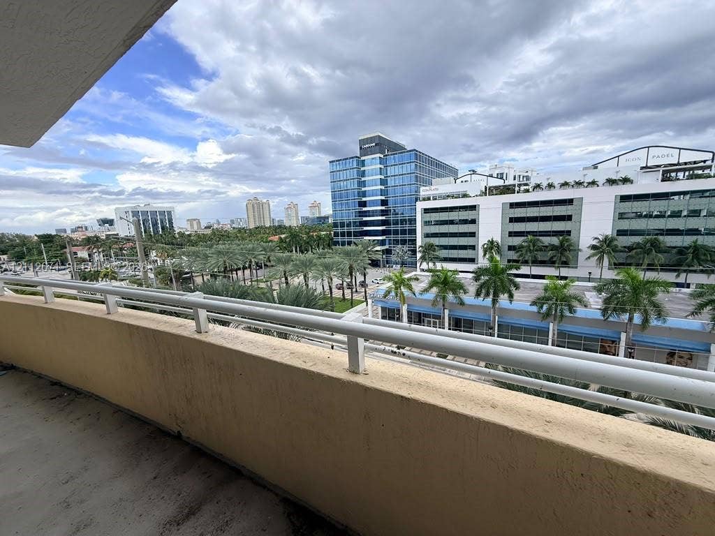 Covered balcony featuring concrete flooring and a white metal safety railing