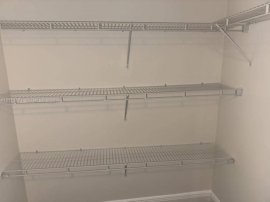 Wall-mounted white wire shelving system featuring three tiered levels of storage