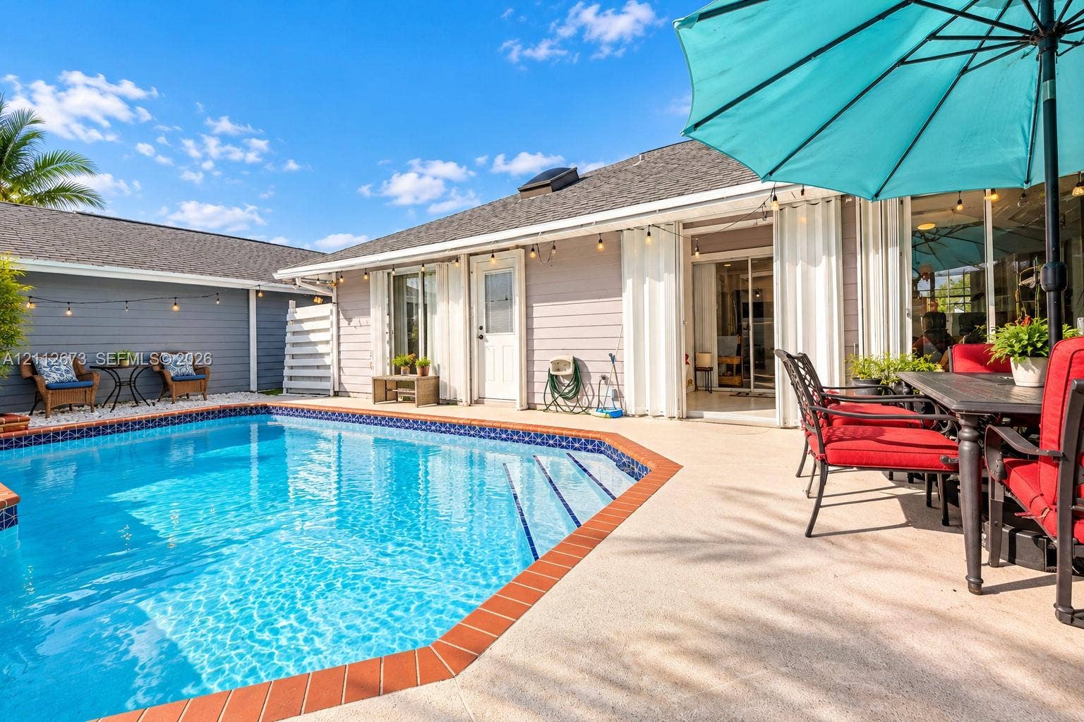10225 SW 141st Court, #0, Miami, Miami, FL 33186 Outdoor living area featuring a swimming pool with tile trim, concrete patio surfacing, horizontal lap siding, and attached string lighting