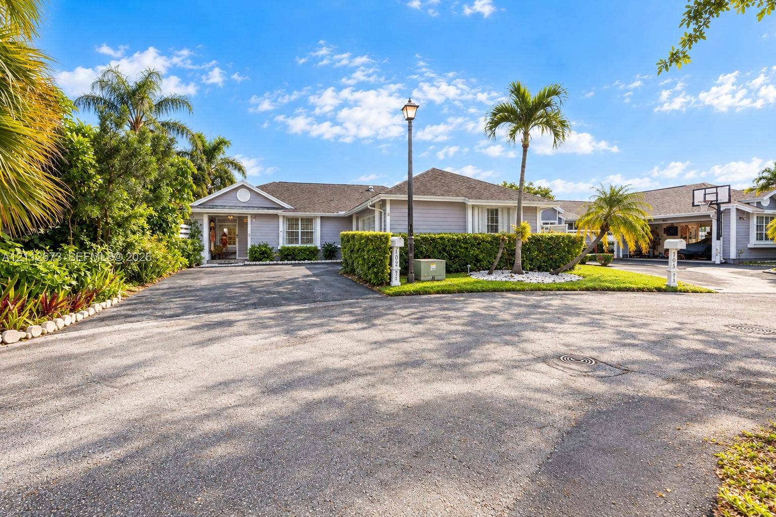 10225 SW 141st Court, #0, Miami, Miami, FL 33186 Exterior facade featuring horizontal siding, a pitched roof, expansive paved driveway, integrated carport, and manicured landscaping