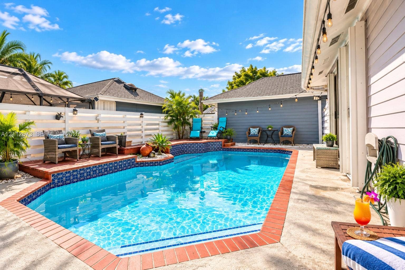 10225 SW 141st Court, #0, Miami, Miami, FL 33186 Outdoor swimming pool featuring decorative tile accents, a brick paver border, concrete patio, and white horizontal privacy fencing