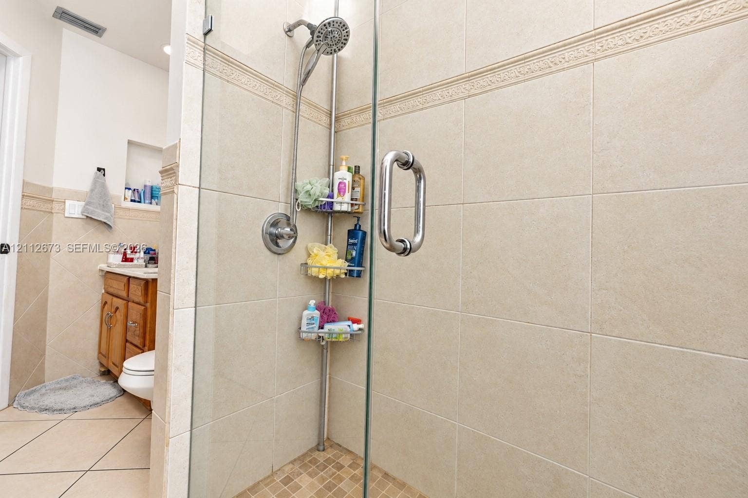 10225 SW 141st Court, #0, Miami, Miami, FL 33186 Walk-in shower featuring glass enclosure, large-format neutral wall tile, decorative tile accent band, and built-in wall niche