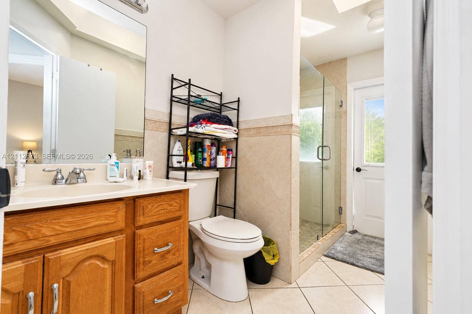 10225 SW 141st Court, #0, Miami, Miami, FL 33186 Bathroom featuring a wood-finish vanity with a molded countertop, walk-in shower with a glass enclosure, decorative tile wainscoting, and tile flooring