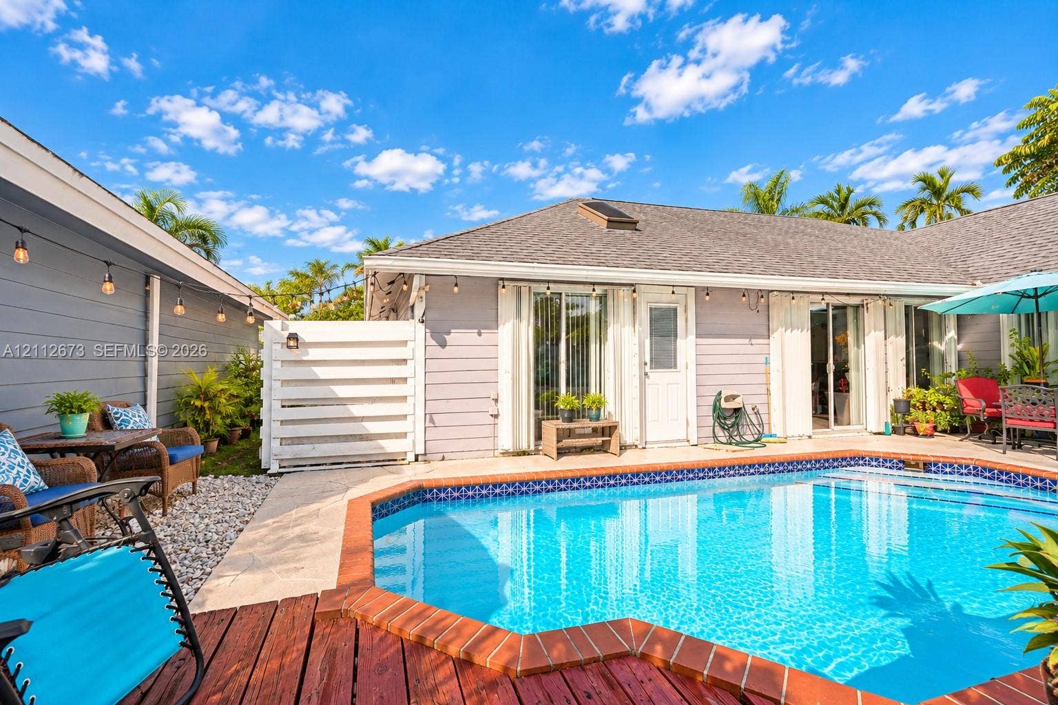 10225 SW 141st Court, #0, Miami, Miami, FL 33186 Outdoor living area featuring a custom-shaped swimming pool with brick coping, wood-finish decking, and light-colored horizontal siding