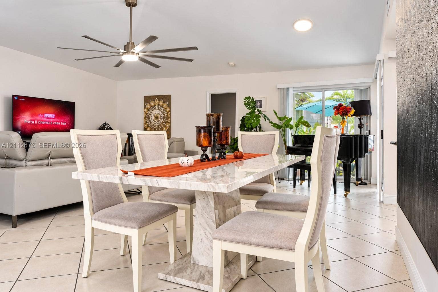 10225 SW 141st Court, #0, Miami, Miami, FL 33186 Open-concept interior featuring light-toned diagonal tile flooring, a multi-blade ceiling fan with integrated lighting, and glass sliding doors